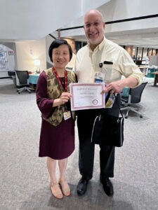 Helen Hu, Ph.D., director of the Educational and Student Success Center, (left) presents a certificate of recognition to David Ussery, Ph.D., a professor in the College of Medicine Department of Biomedical Informatics, for earning credits in the center's commitment to teaching excellence program. 