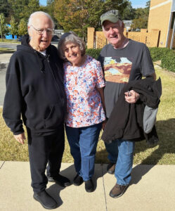 Three people posing for a photo next to the Residence Hall.